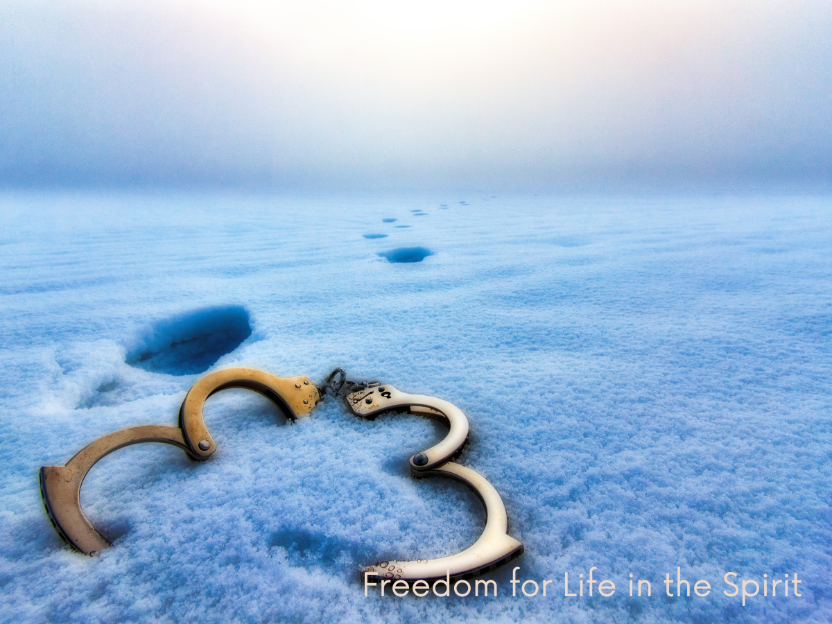 An image of freedom, with broken handcuffs in the snow and footprints walking away