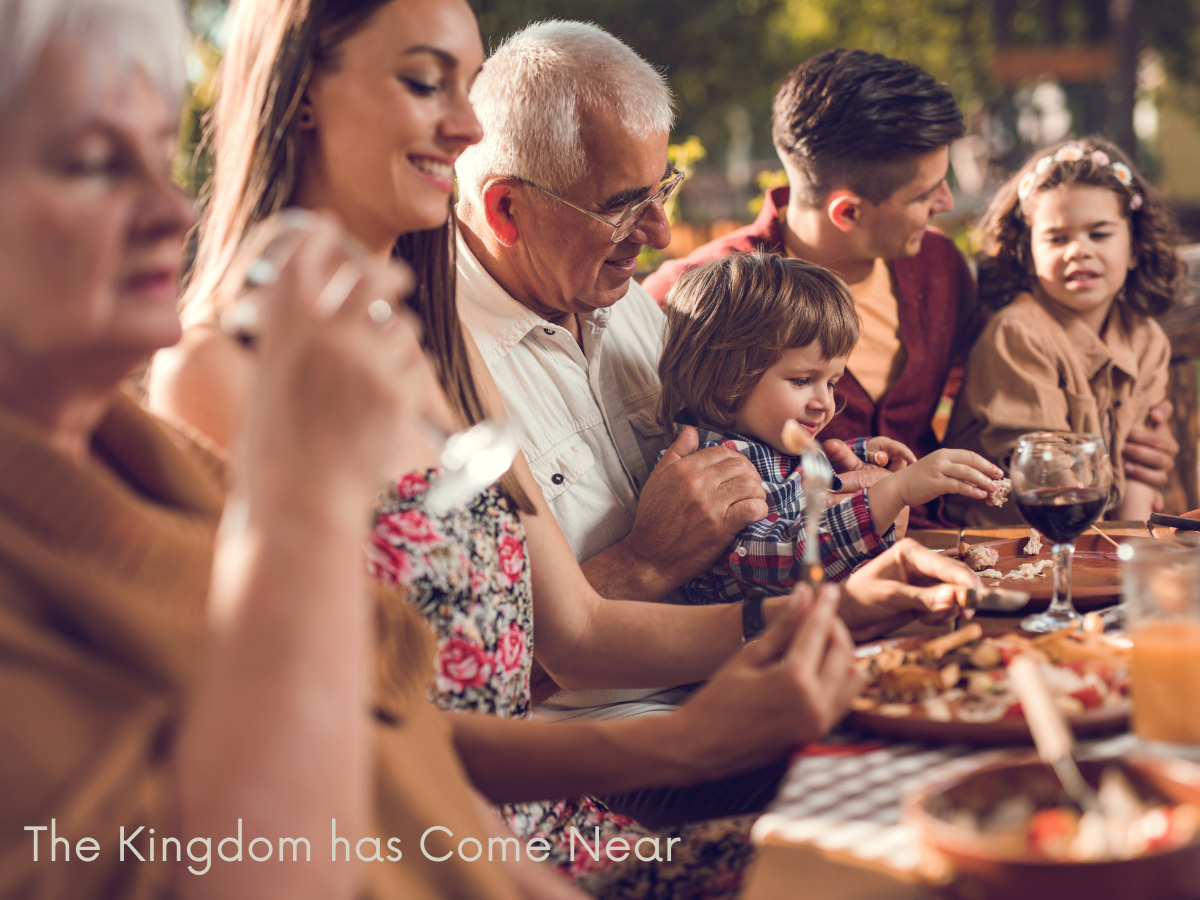 A photo of a family gathered around a table to illustrate love and relationship in the kingdom of God